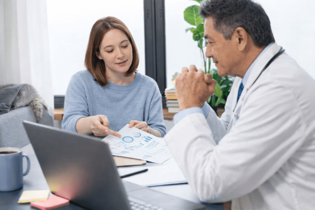 Doctor consulting female patient and reviewing medical charts in clinic