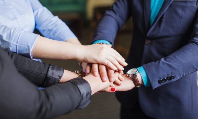 people-standing-office-holding-hands-together